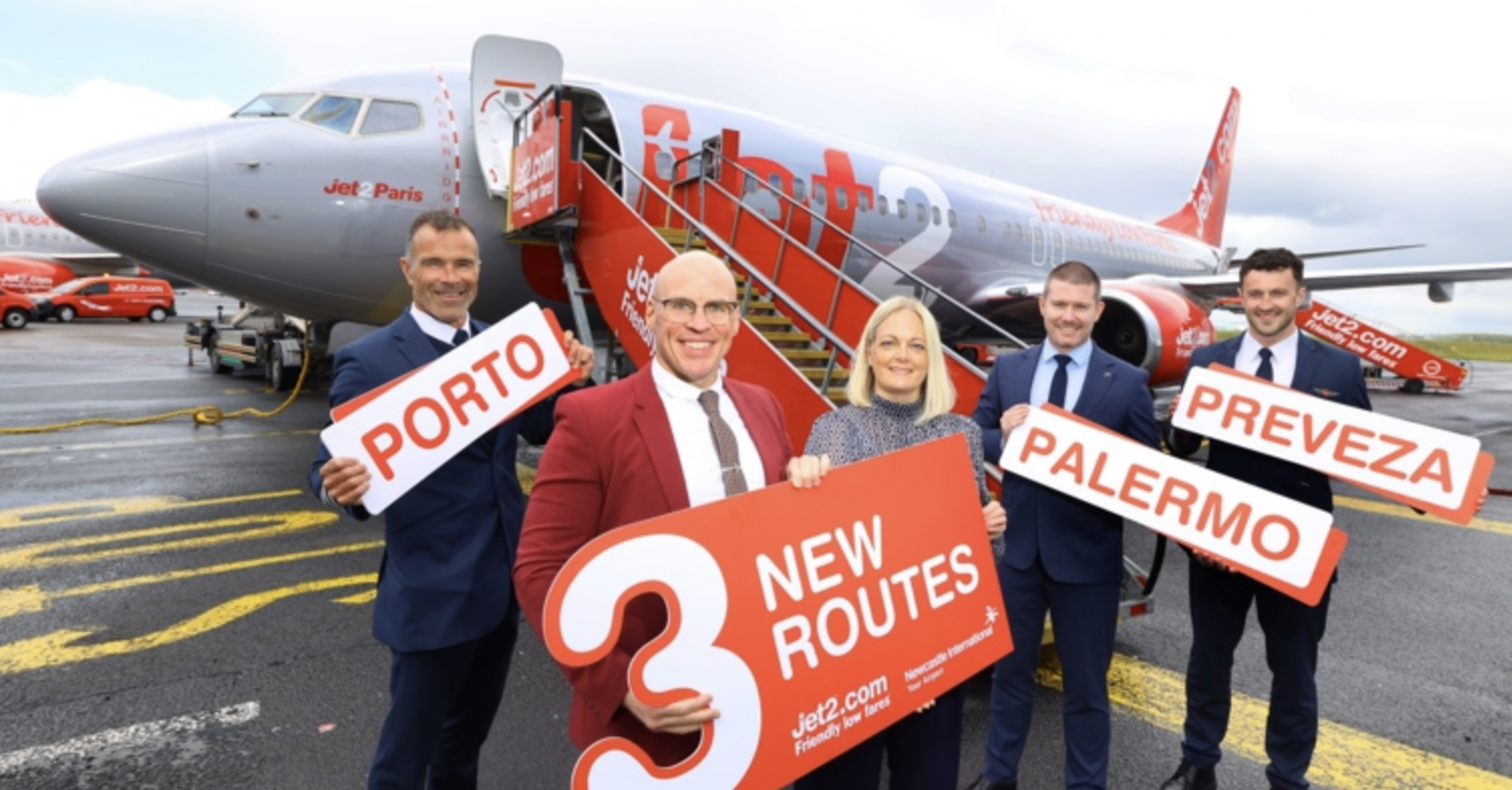Jet2 team holding new route signs beside an aircraft