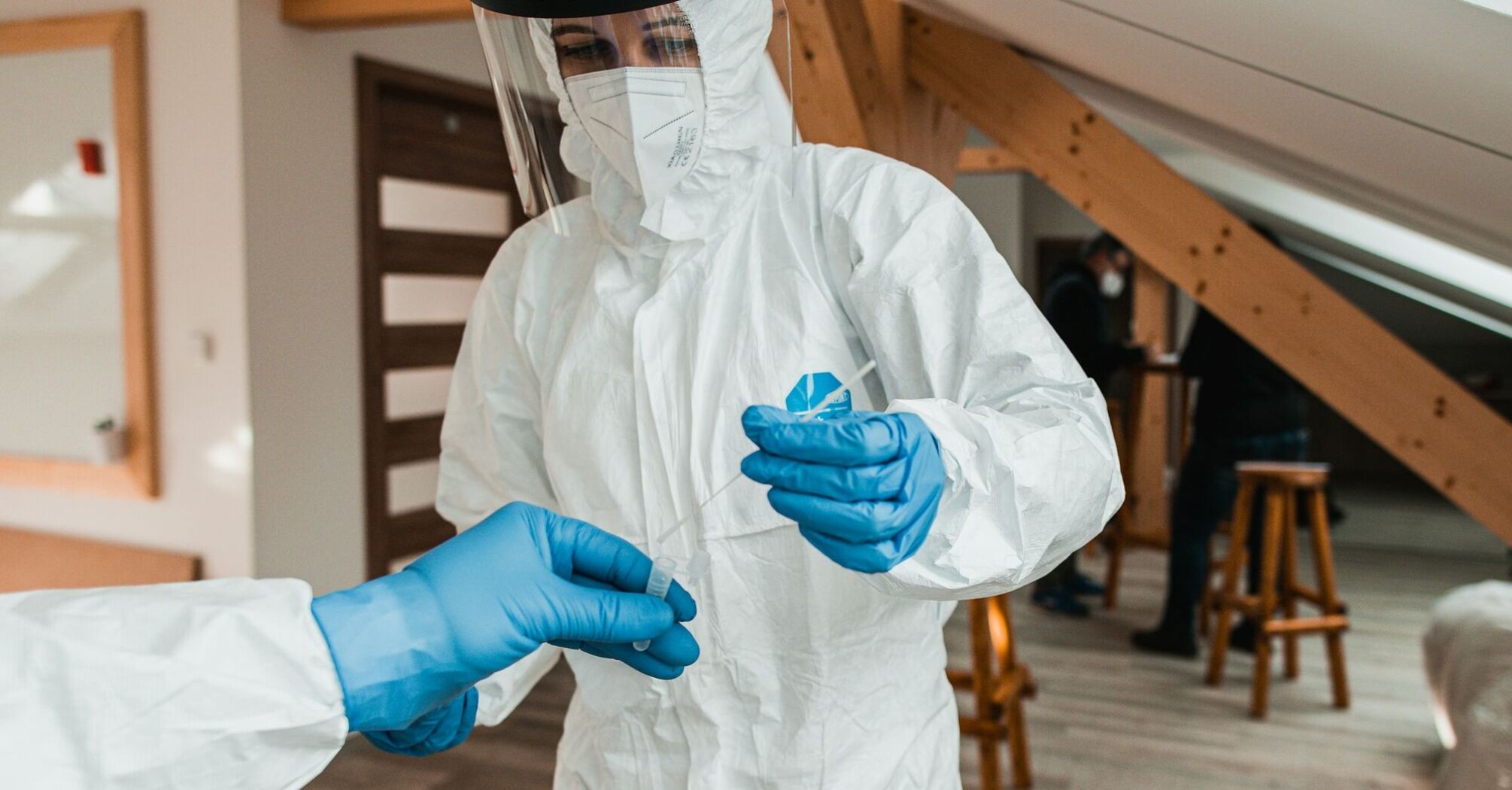 Healthcare worker in protective equipment handling a test sample