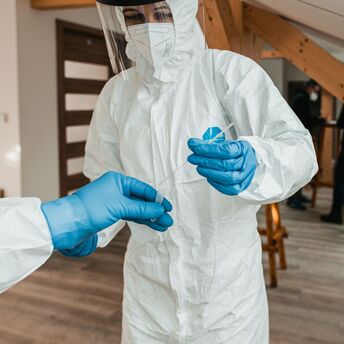 Healthcare worker in protective equipment handling a test sample
