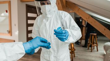 Healthcare worker in protective equipment handling a test sample