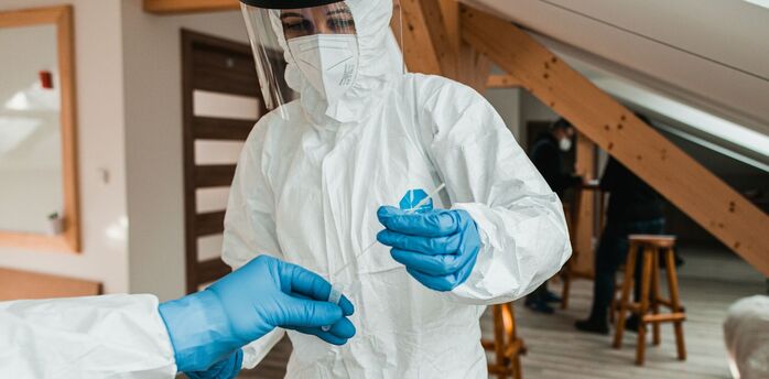 Healthcare worker in protective equipment handling a test sample