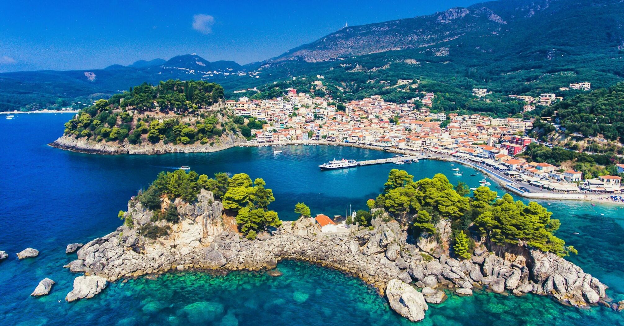 Coastal town in Greece with turquoise water, hills and a small harbour