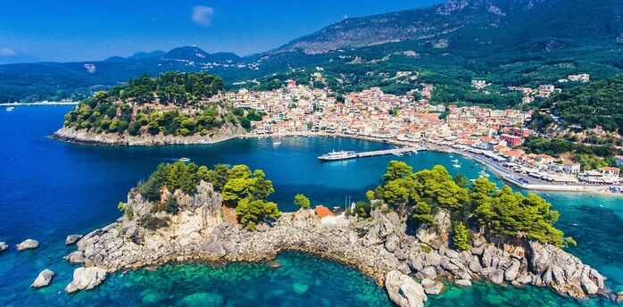 Coastal town in Greece with turquoise water, hills and a small harbour