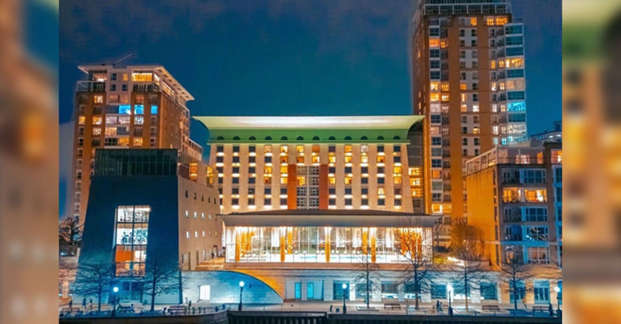 Canary Riverside Plaza hotel building lit up at night beside the water