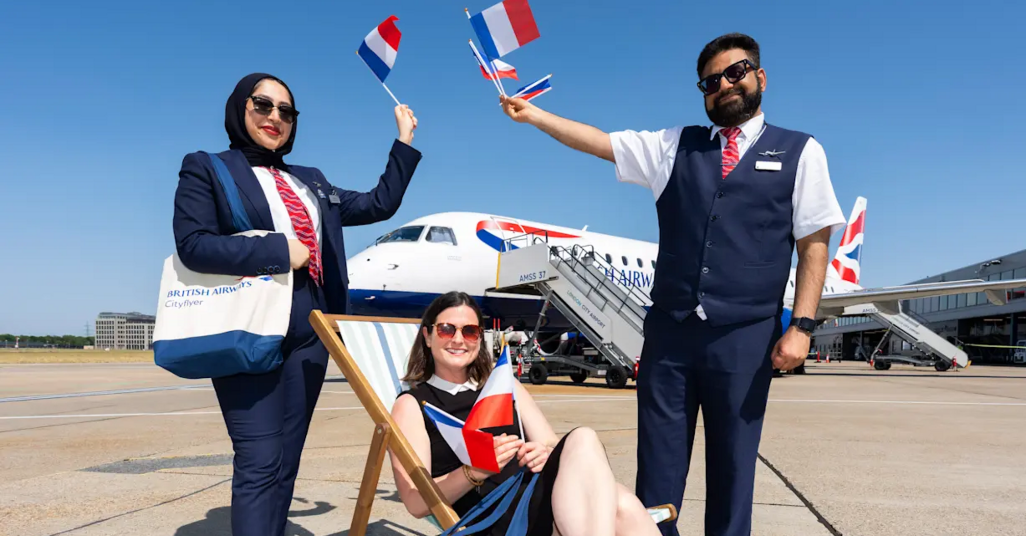 British Airways Cityflyer staff holding French flags beside an aircraft at London City Airport
