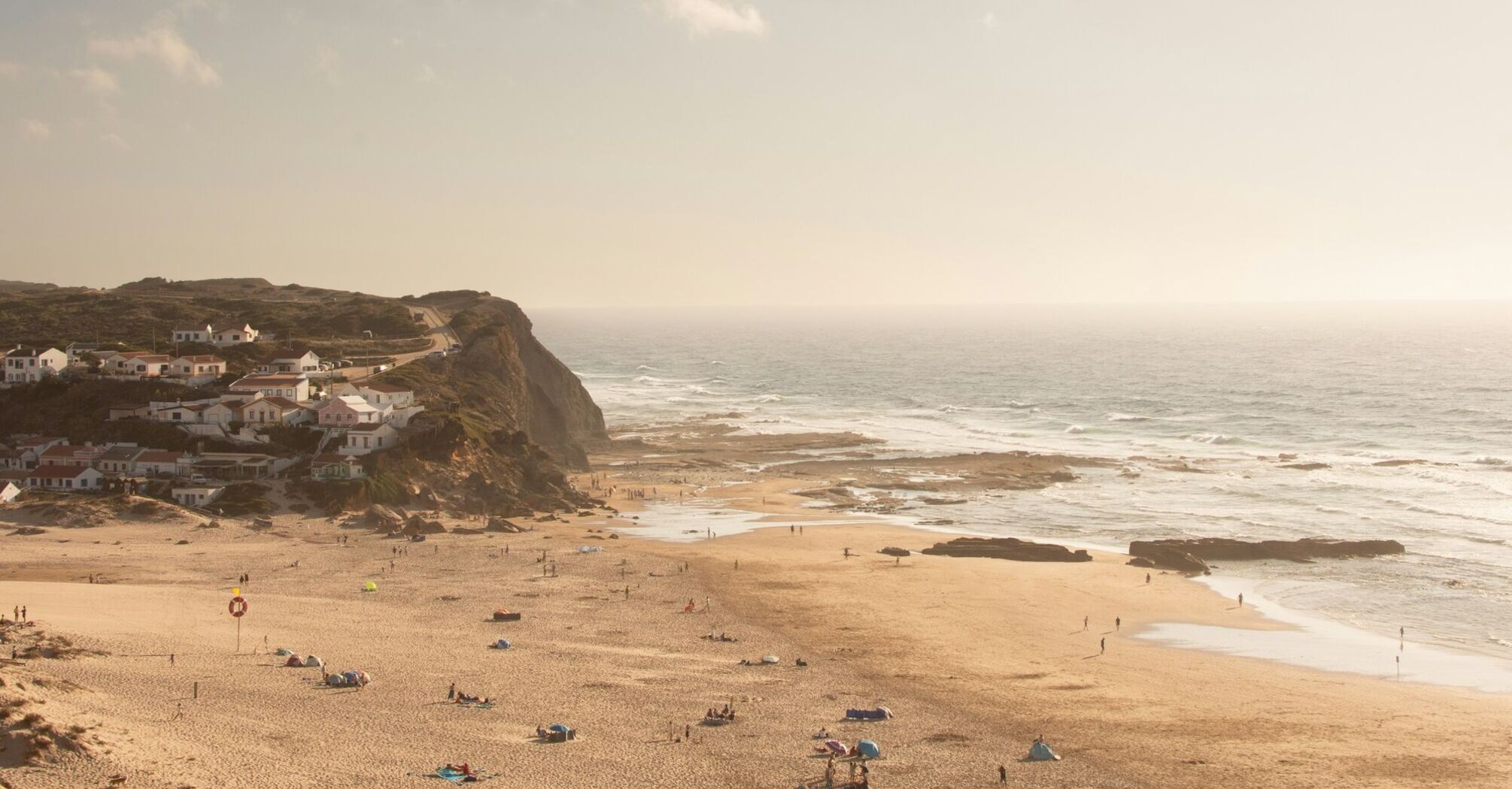 Monte Clérigo beach with cliffs, village houses and Atlantic waves