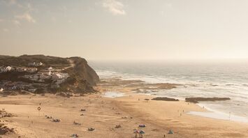 Monte Clérigo beach with cliffs, village houses and Atlantic waves
