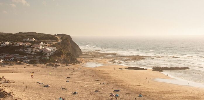 Monte Clérigo beach with cliffs, village houses and Atlantic waves