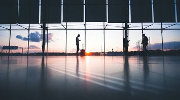 Passengers waiting inside an airport terminal at sunset