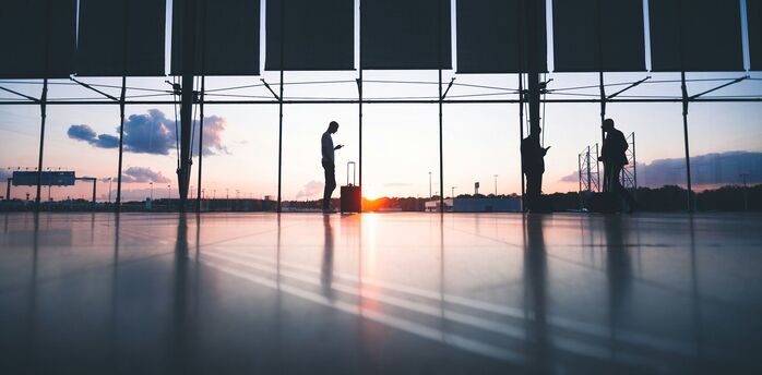 Passengers waiting inside an airport terminal at sunset