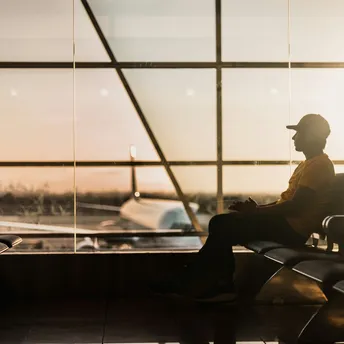 Passenger waiting in airport terminal with aircraft visible outside
