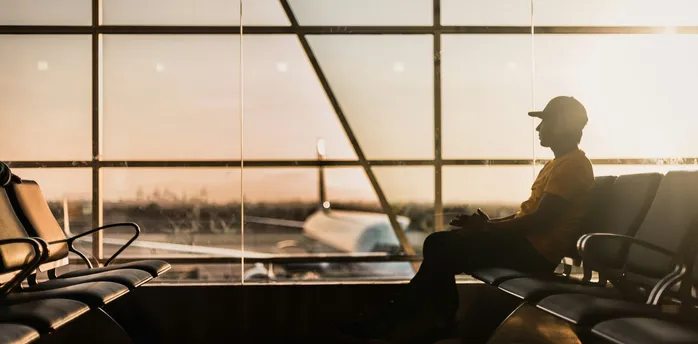 Passenger waiting in airport terminal with aircraft visible outside