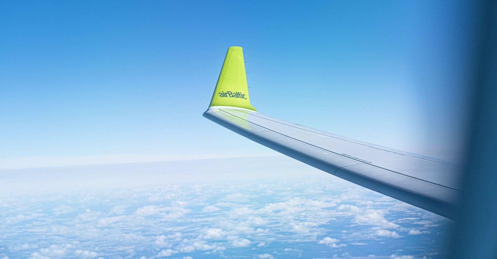 airBaltic aircraft wing seen above clouds during a flight