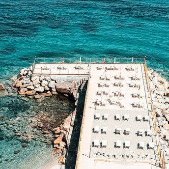 Sun loungers lined up beside clear blue sea
