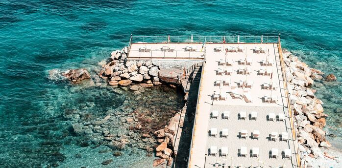 Sun loungers lined up beside clear blue sea