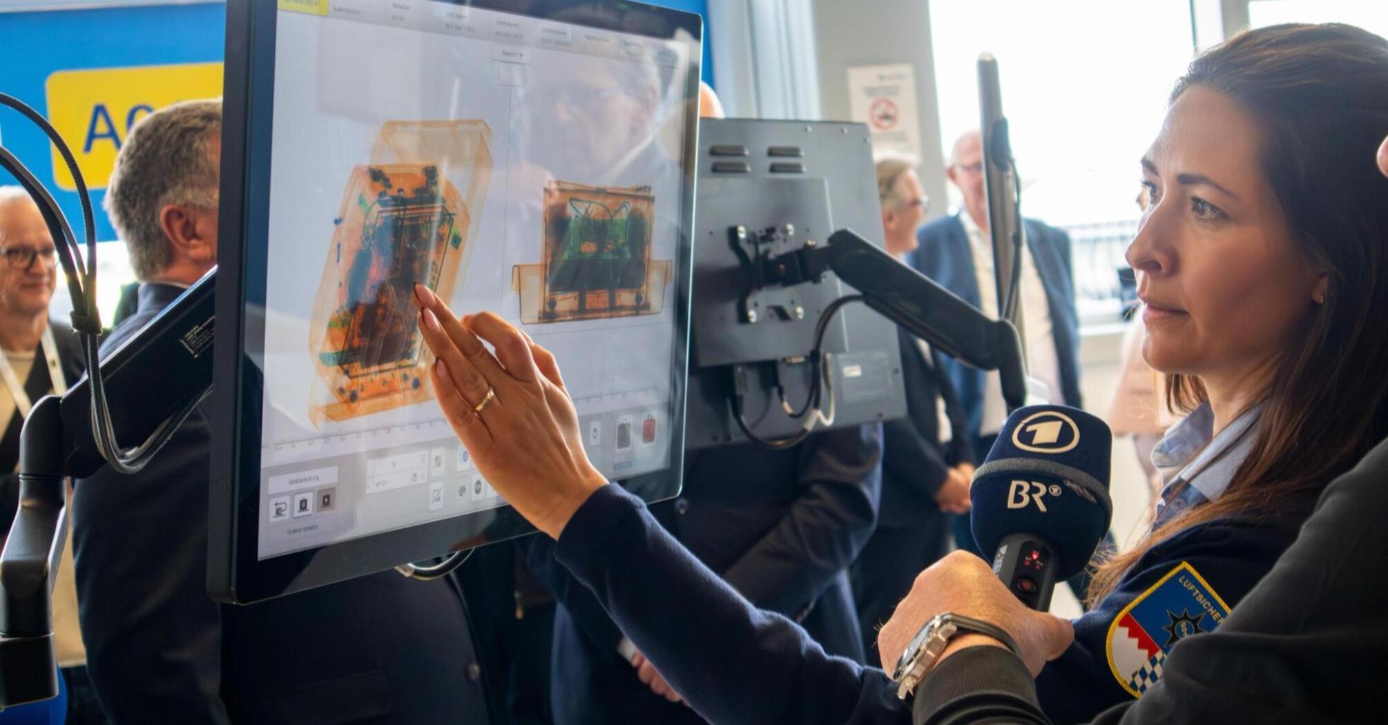 Airport staff demonstrating CT baggage screening technology
