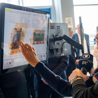 Airport staff demonstrating CT baggage screening technology