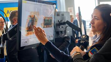 Airport staff demonstrating CT baggage screening technology