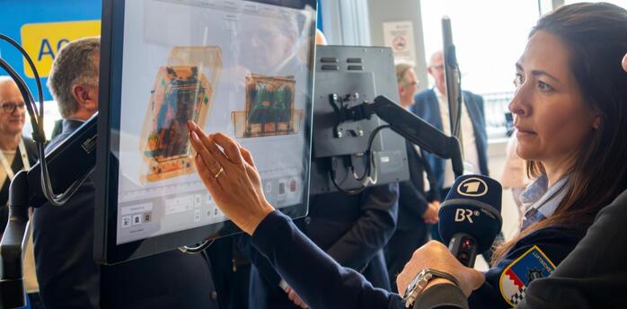 Airport staff demonstrating CT baggage screening technology