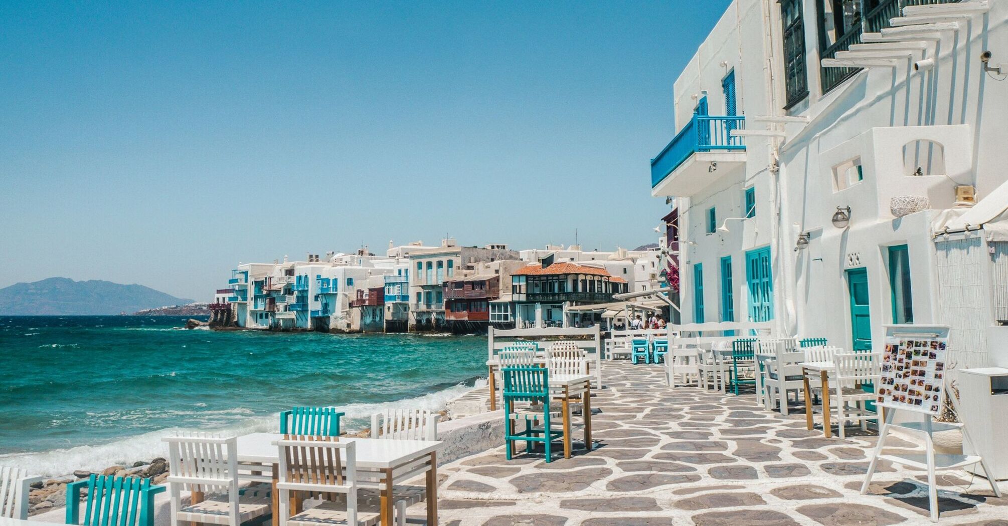 Whitewashed waterfront buildings and outdoor tables in Mykonos