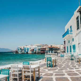 Whitewashed waterfront buildings and outdoor tables in Mykonos
