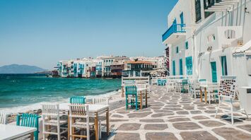 Whitewashed waterfront buildings and outdoor tables in Mykonos