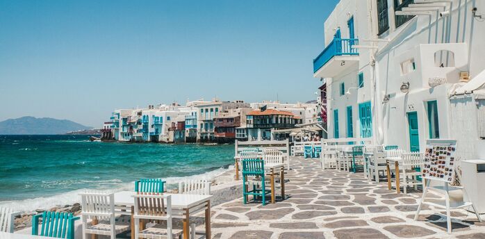 Whitewashed waterfront buildings and outdoor tables in Mykonos