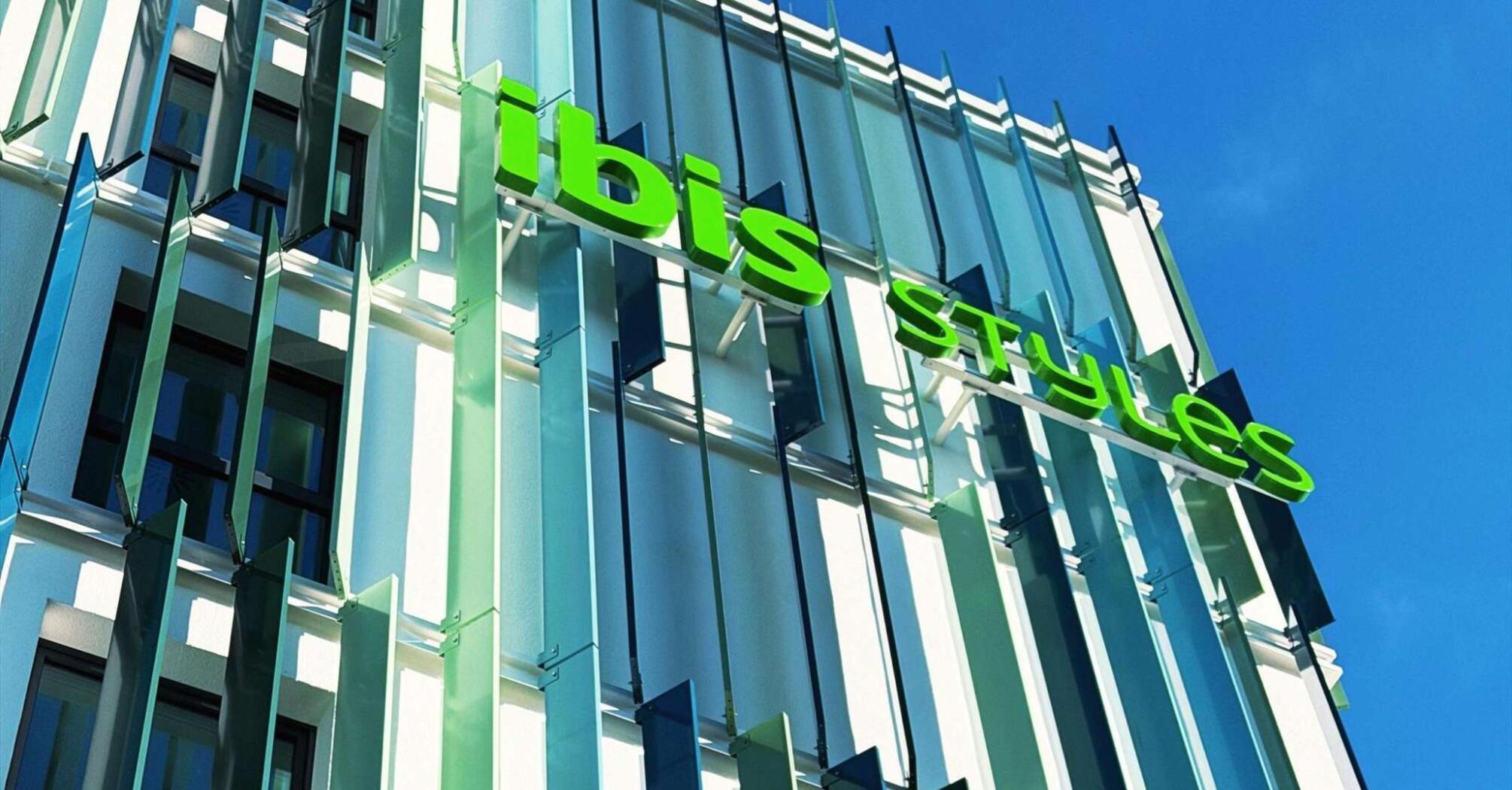 Exterior of the ibis Styles Munich Airport hotel with green signage