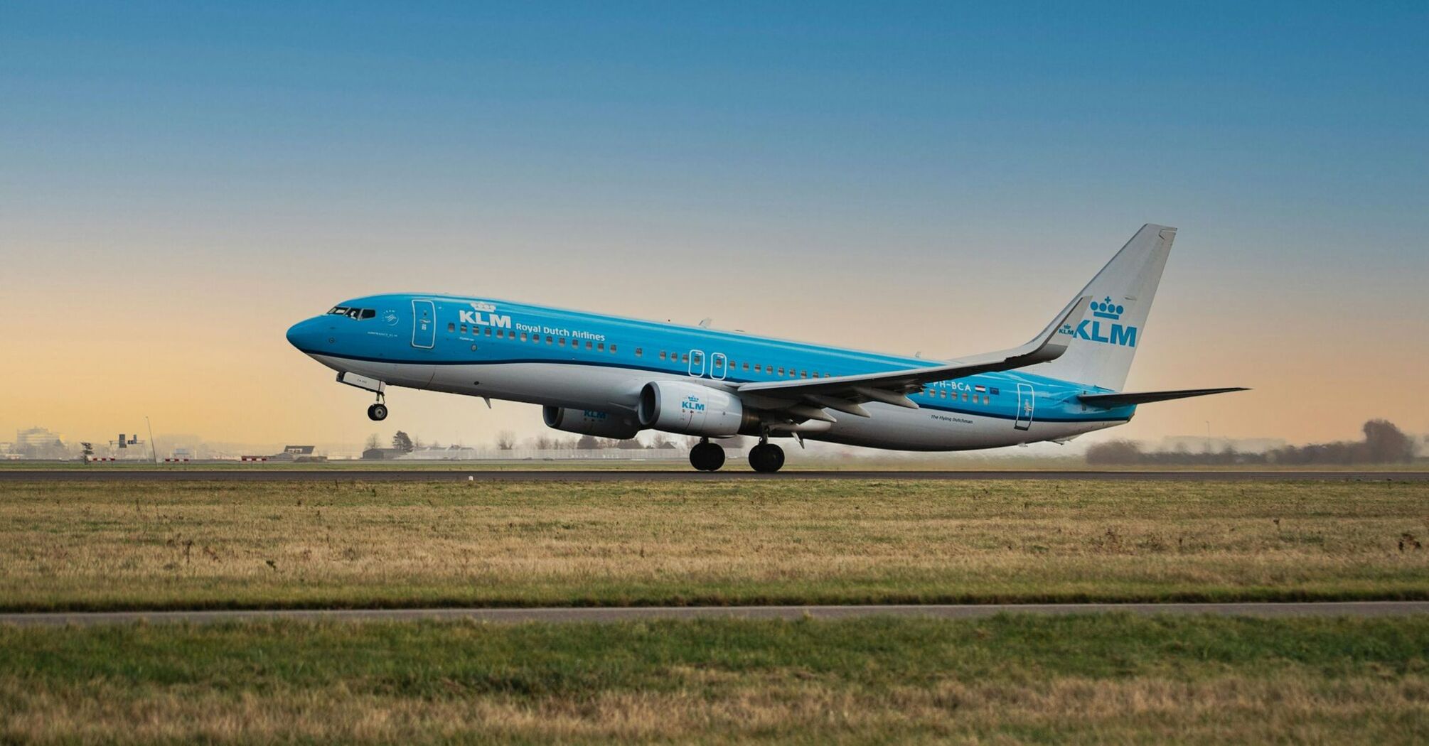 KLM aircraft taking off from a runway at sunset