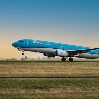 KLM aircraft taking off from a runway at sunset