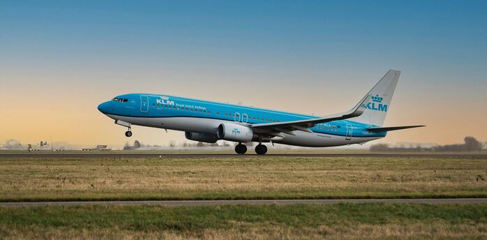 KLM aircraft taking off from a runway at sunset
