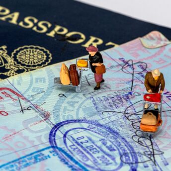 Small traveller figures standing on passport pages with visa stamps