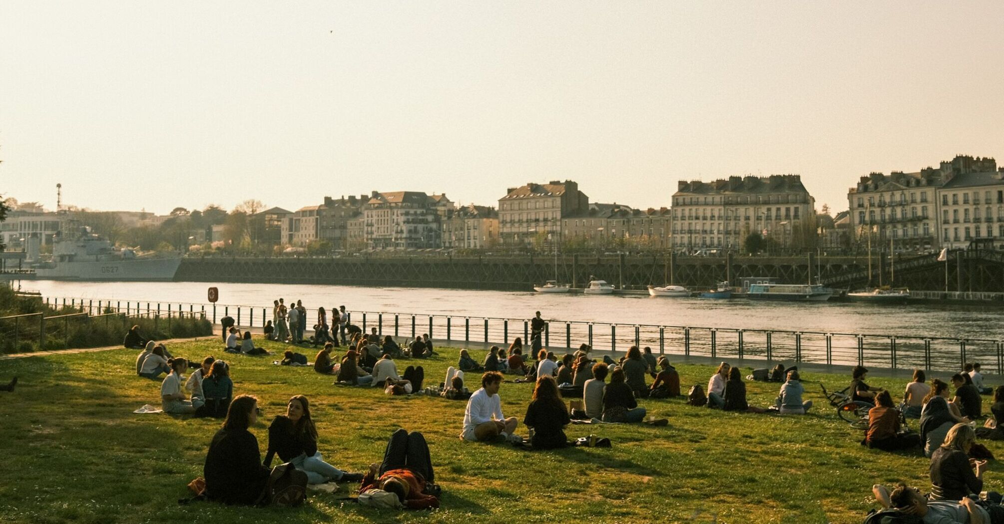 People sitting by the river in Nantes at sunset