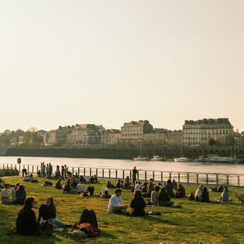 People sitting by the river in Nantes at sunset
