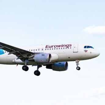 Eurowings aircraft flying against a pale blue sky