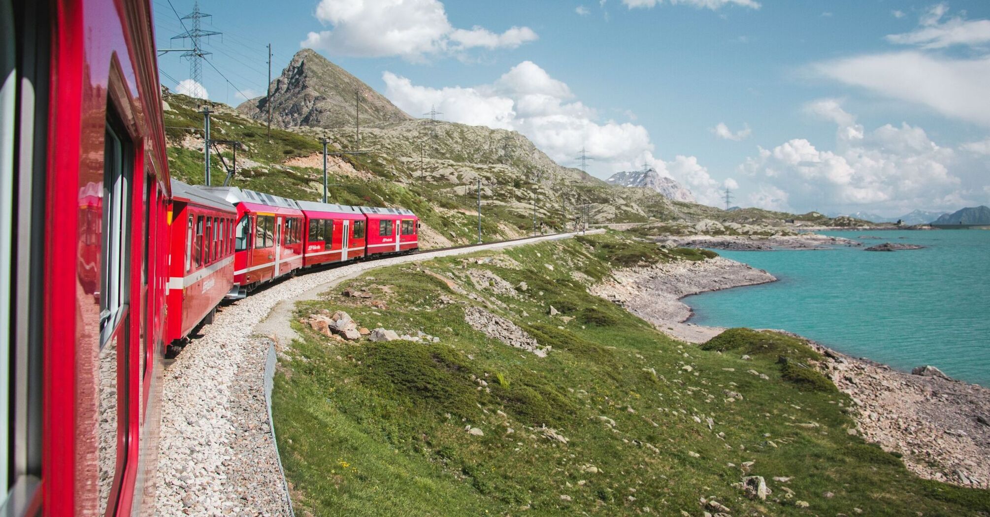 Red train passing a mountain lake