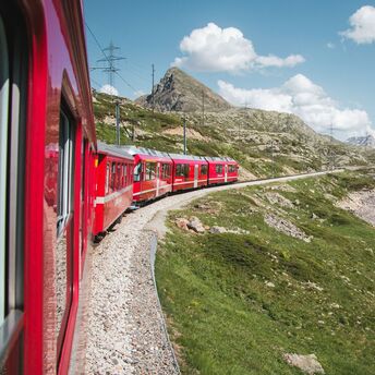 Red train passing a mountain lake