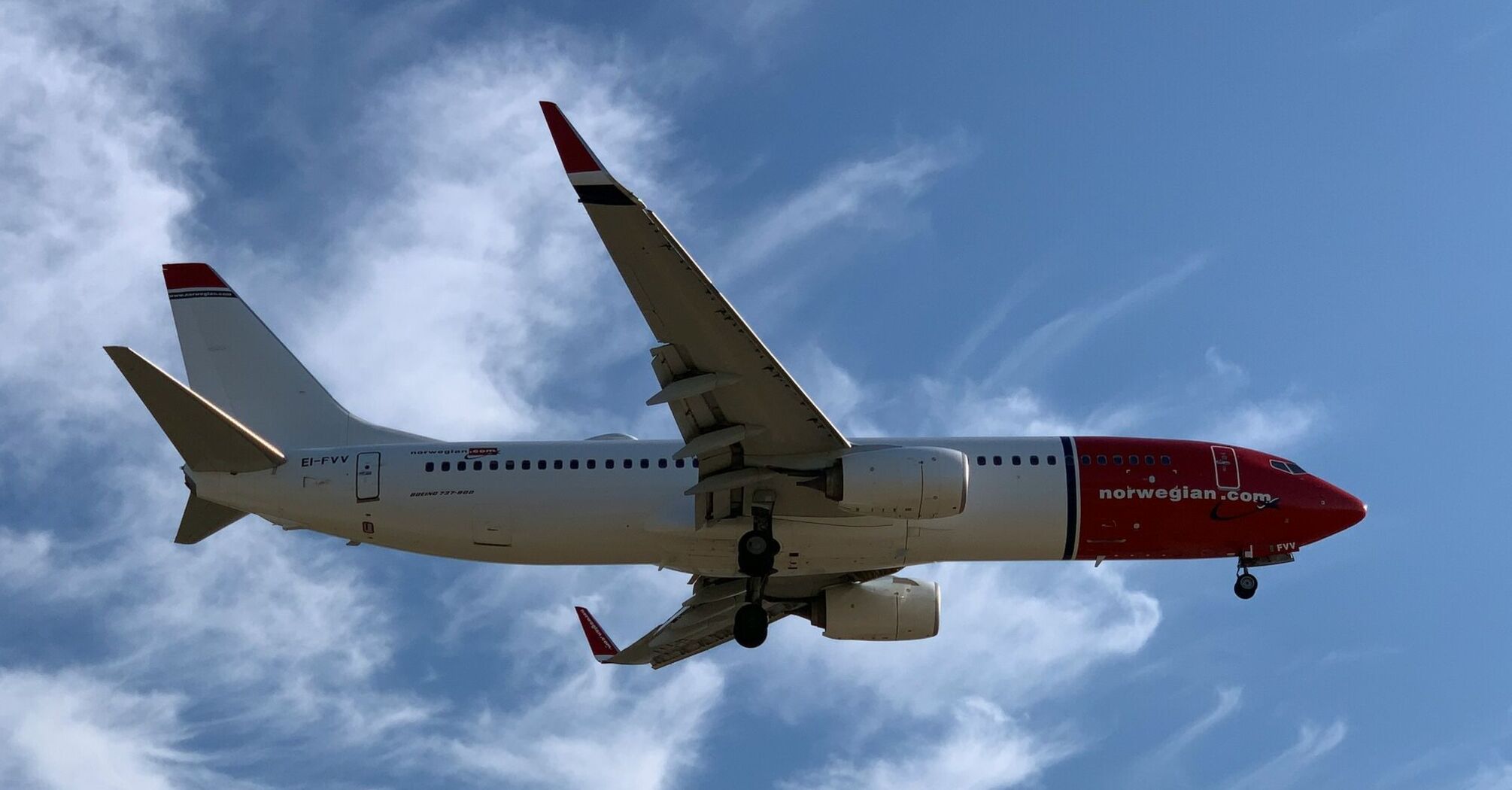Norwegian aircraft flying against a blue sky