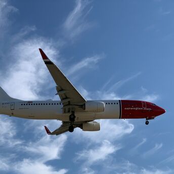 Norwegian aircraft flying against a blue sky