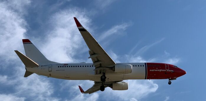 Norwegian aircraft flying against a blue sky