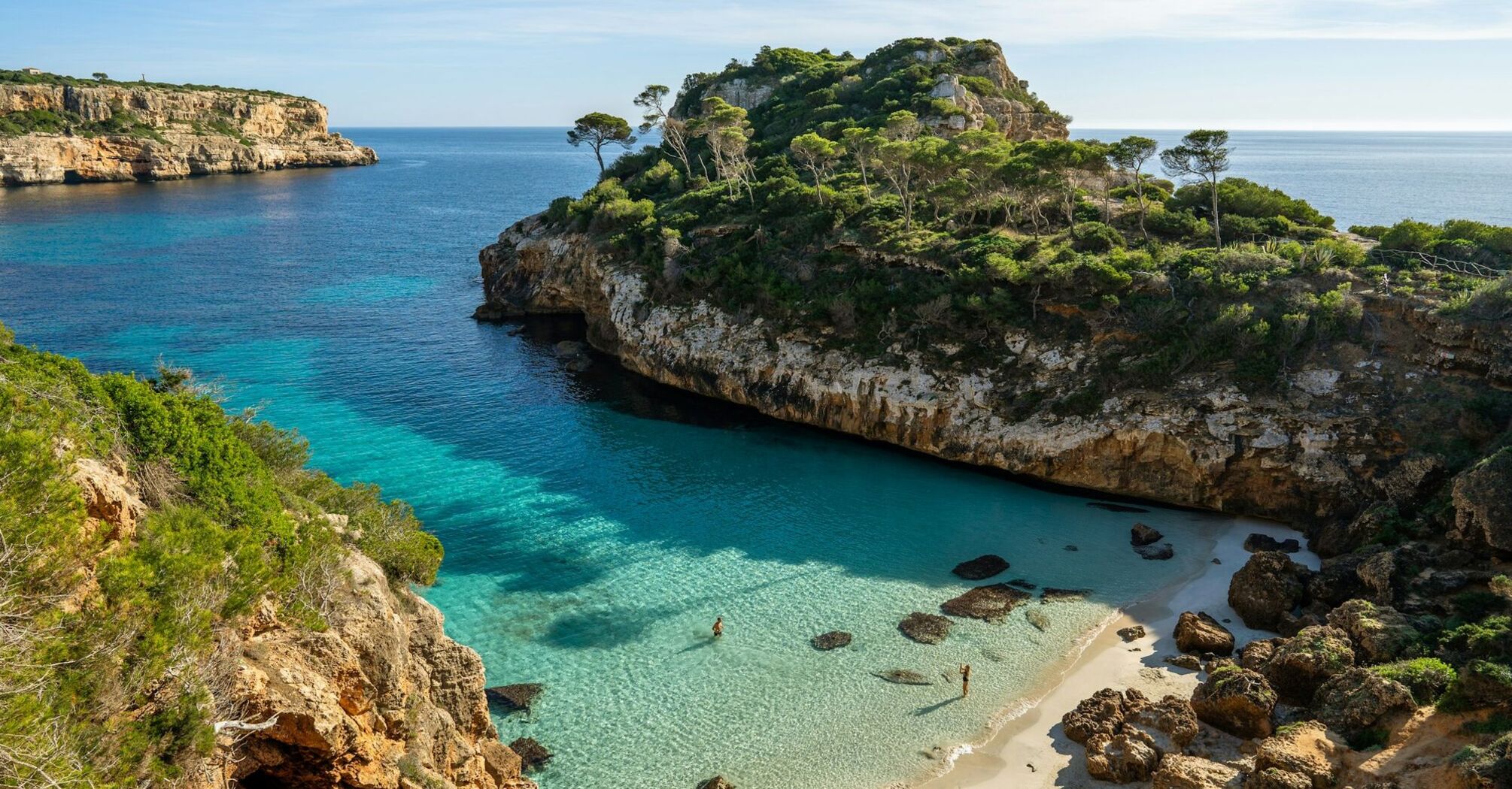 Mallorca cove with clear turquoise water and rocky pine-covered cliffs