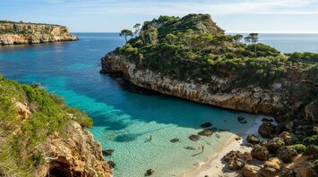 Mallorca cove with clear turquoise water and rocky pine-covered cliffs