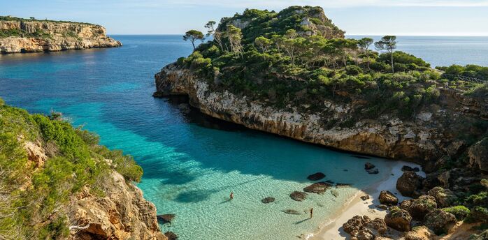 Mallorca cove with clear turquoise water and rocky pine-covered cliffs