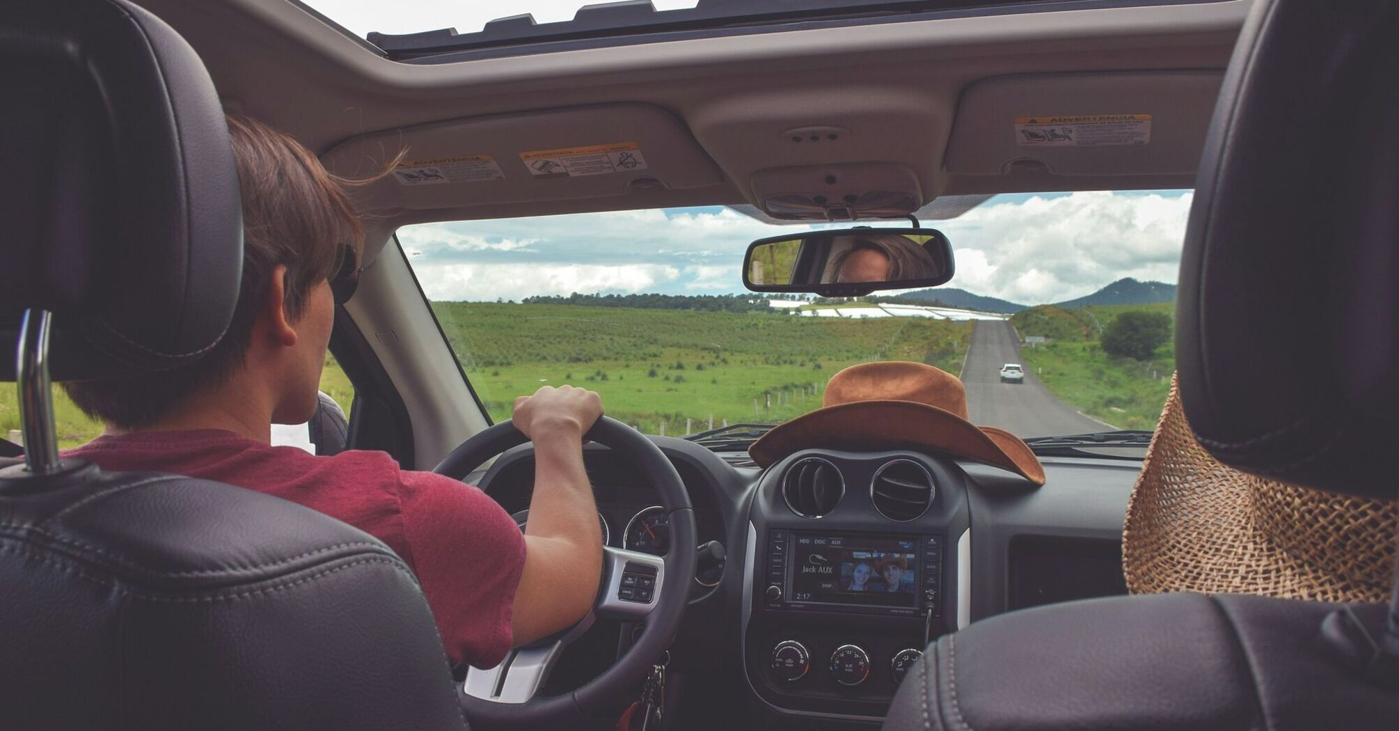 Driver on a summer road trip viewed from inside a car