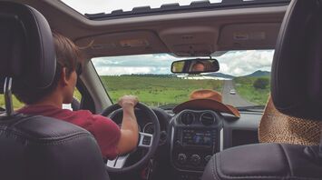 Driver on a summer road trip viewed from inside a car