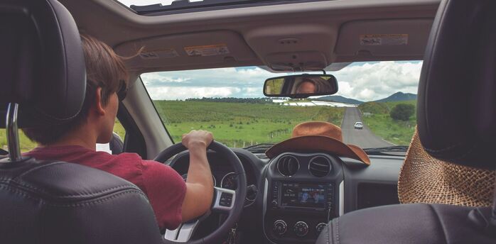 Driver on a summer road trip viewed from inside a car