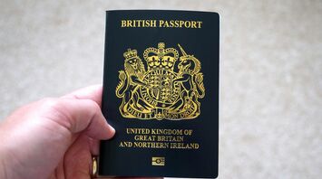Hand holding a British passport against a neutral background