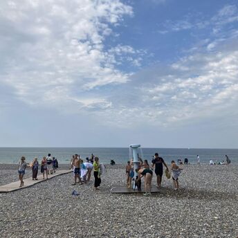 Beachgoers using a shower on a pebbled beach