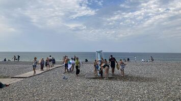 Beachgoers using a shower on a pebbled beach
