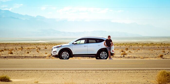 Driver standing beside a rental car on a road